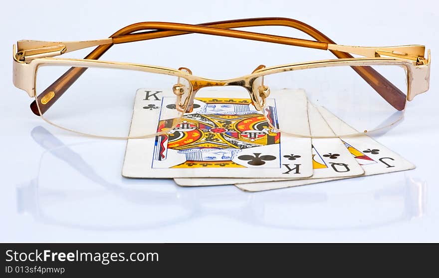 Golden frame reading glass on 3 used playing cards