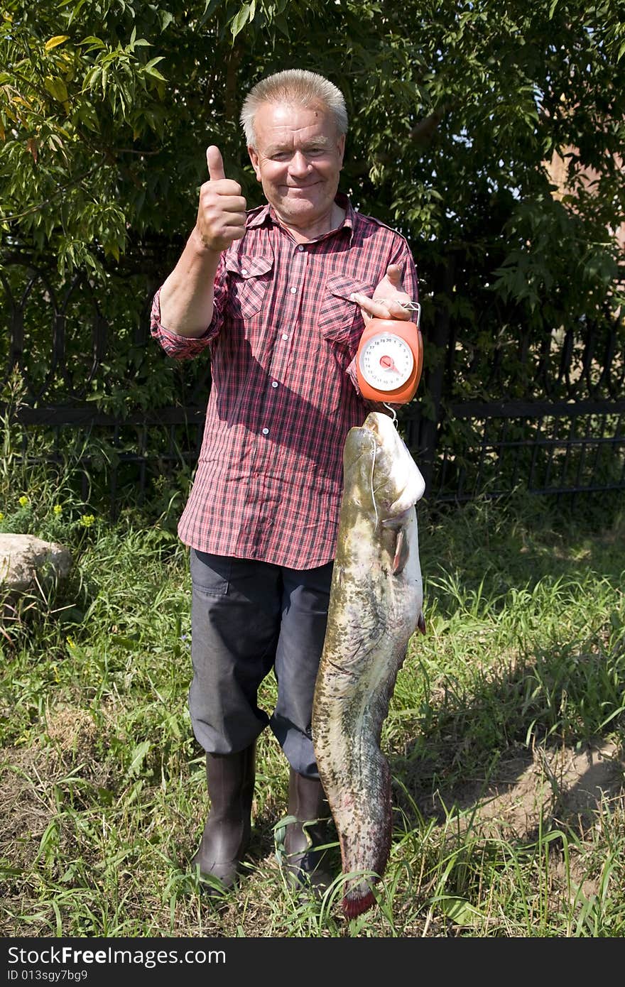 Happy and proud fisher demonstrates catched cat fish of 7 kilo weight. Happy and proud fisher demonstrates catched cat fish of 7 kilo weight