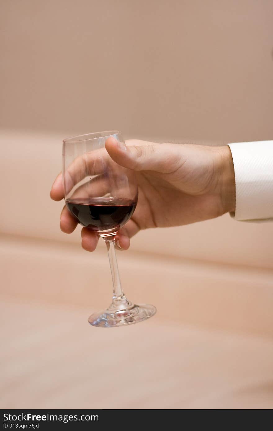 Man's hand keeps a glass with a red wine on light background