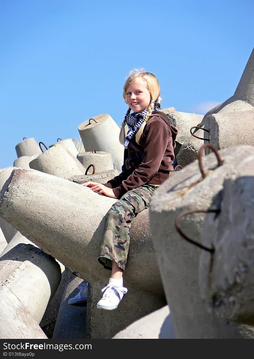 Young blond girl siting on the breakwater. Young blond girl siting on the breakwater.