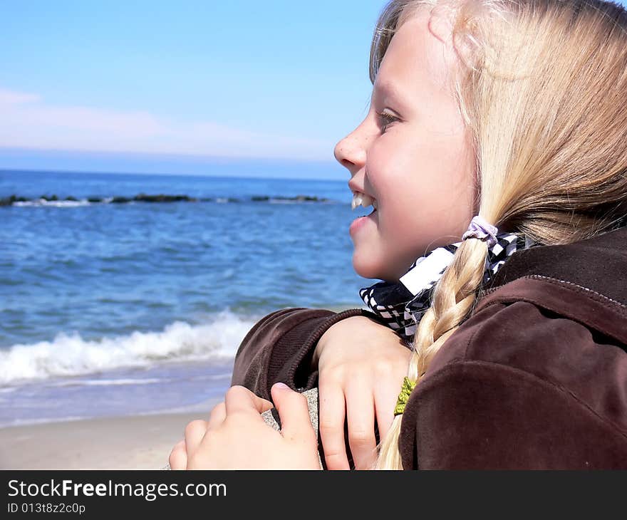 Young blond girl smiling at seaside - close up