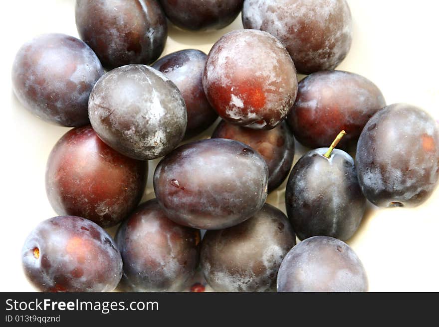 Closeup of purple plums over white