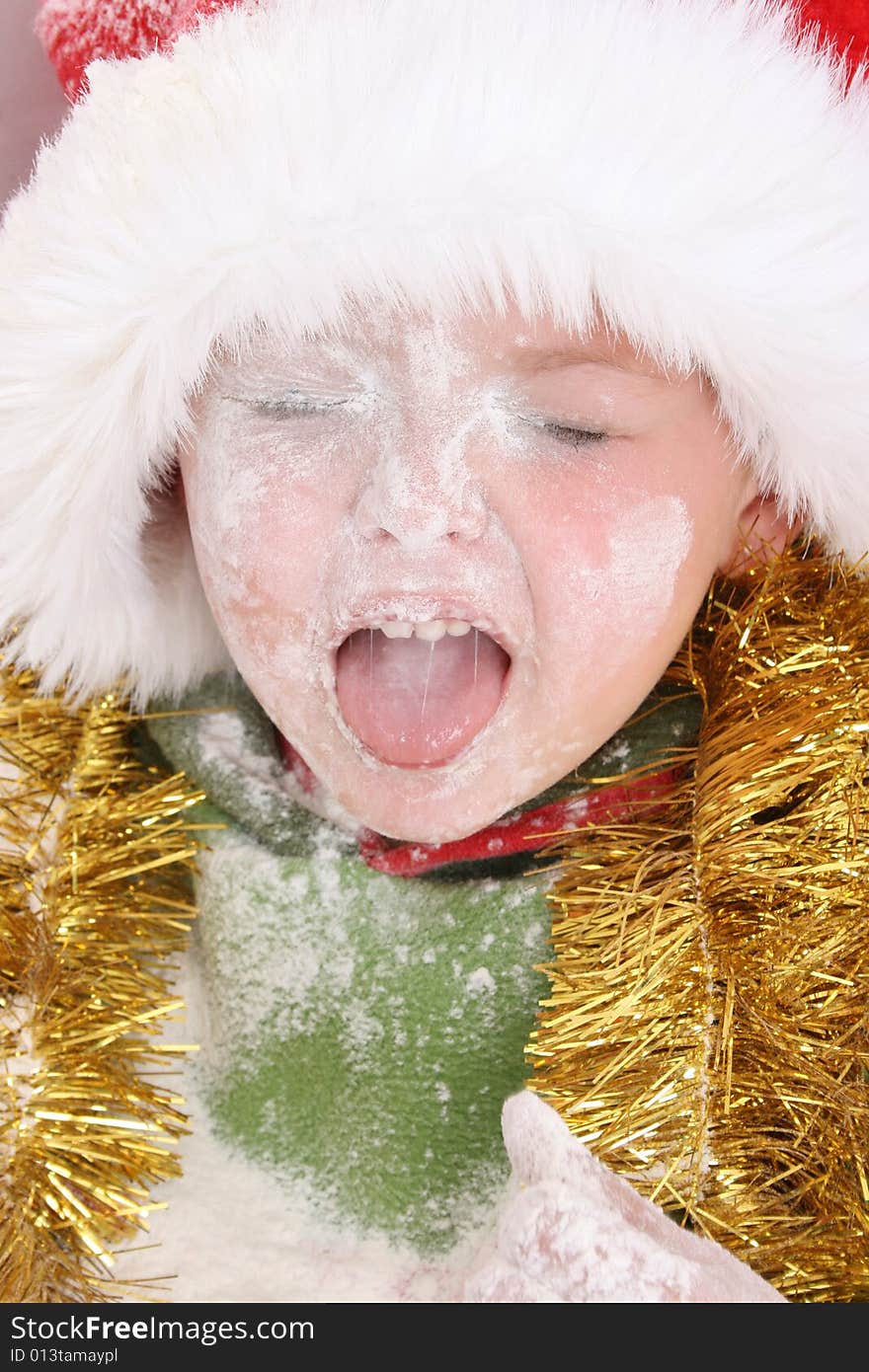 Toddler wearing a christmas hat, covered in flour. Toddler wearing a christmas hat, covered in flour