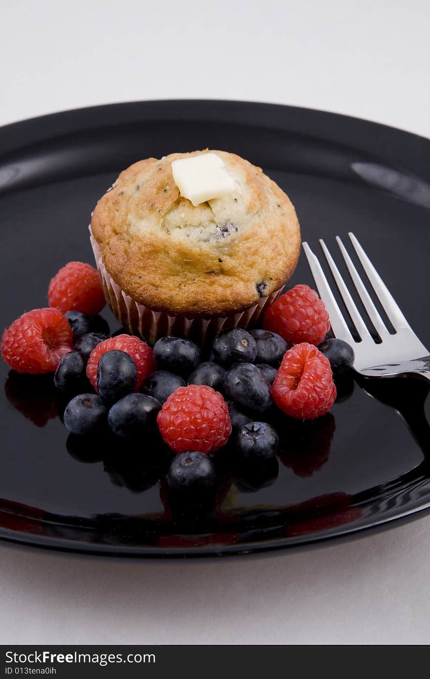 Hot muffins & fresh berries on black plate with fork. Hot muffins & fresh berries on black plate with fork