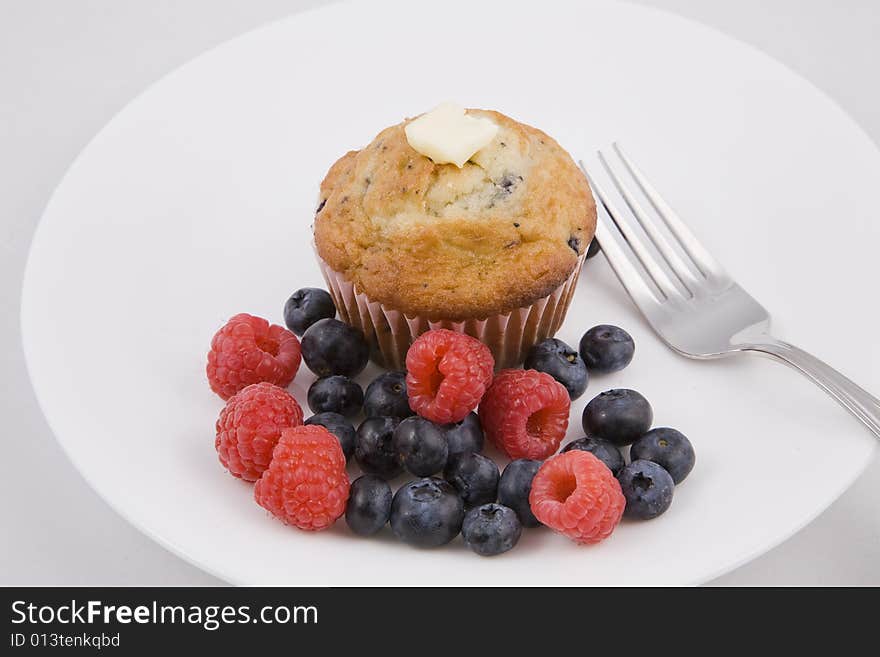 Hot muffins & fresh berries on white plate with fork. Hot muffins & fresh berries on white plate with fork