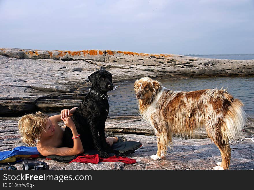 Boy dries off on a rocky shoal after swimming in Georgian bay with the dogs - an Australian Shepperd and Portuguese Water Dog. Boy dries off on a rocky shoal after swimming in Georgian bay with the dogs - an Australian Shepperd and Portuguese Water Dog