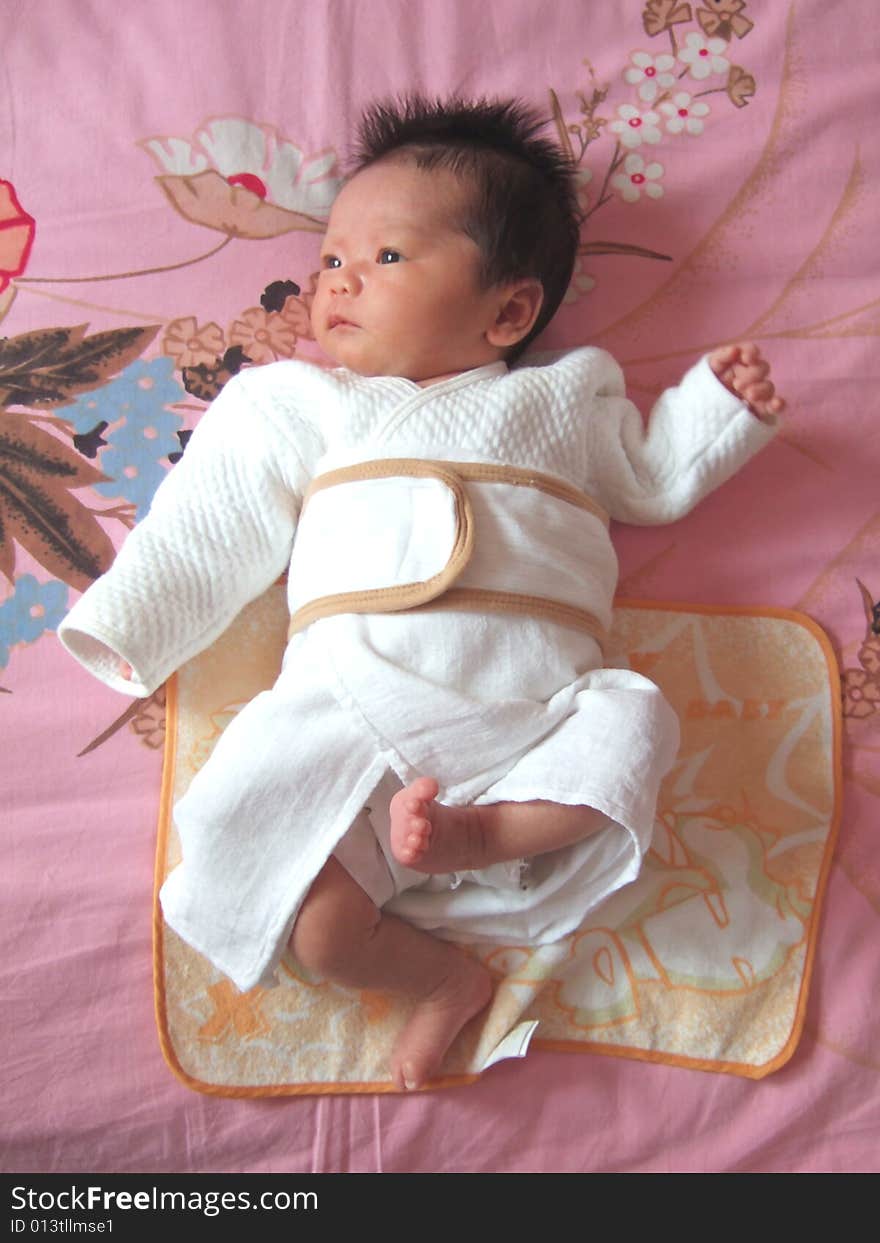 Lovely baby in white on a bed