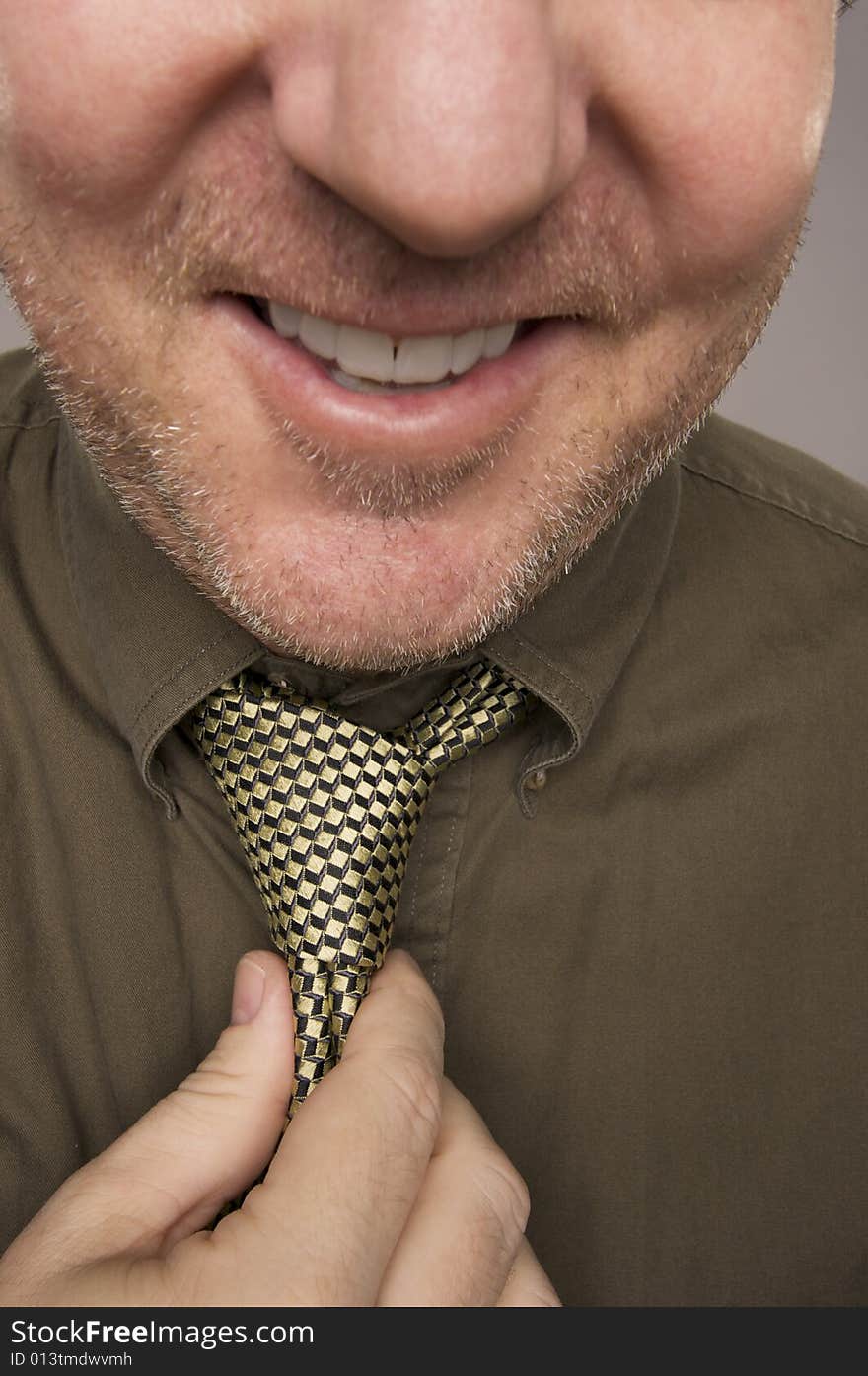 Smiling Man Fixing Tie Against Grey Background