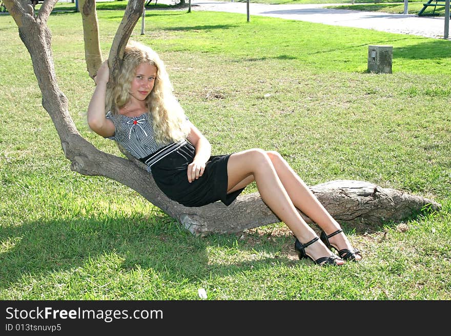 Pretty blond girl with long hair on the tree. Pretty blond girl with long hair on the tree.