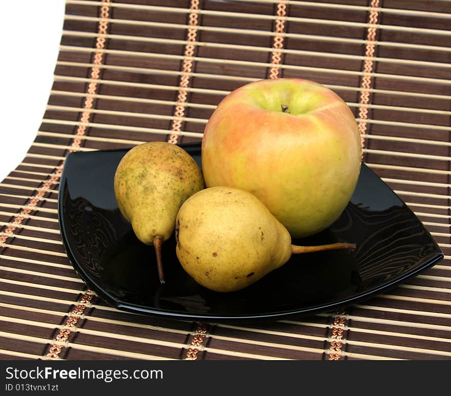 Apple and pears on a black plate on a 
napkin