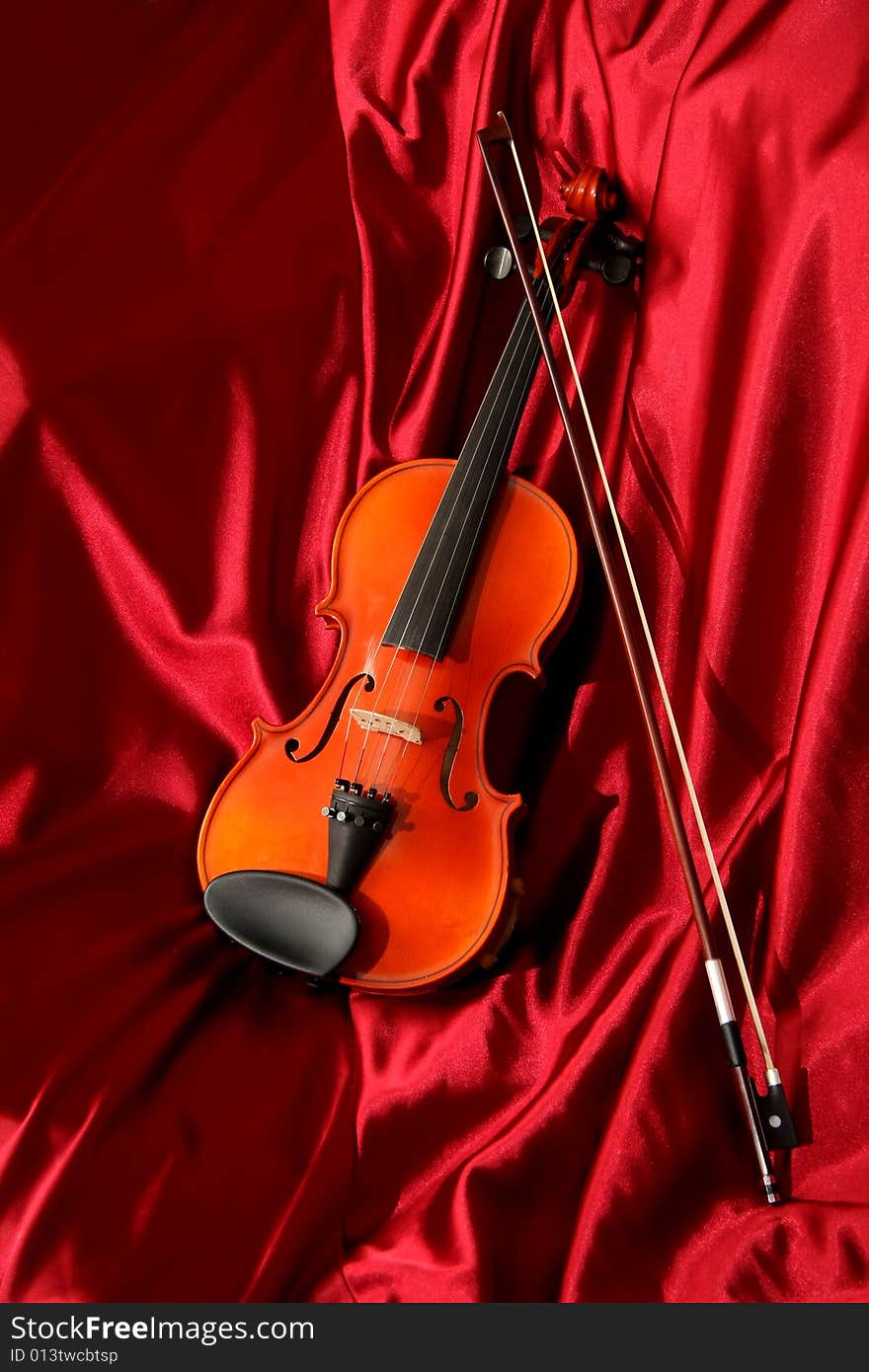 Violin and bow on red silk, music background