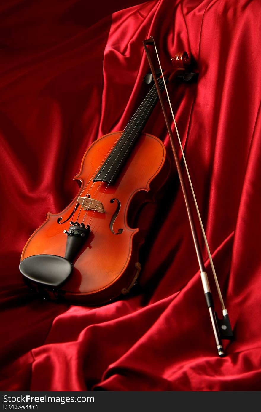 Violin and bow on red silk, music background