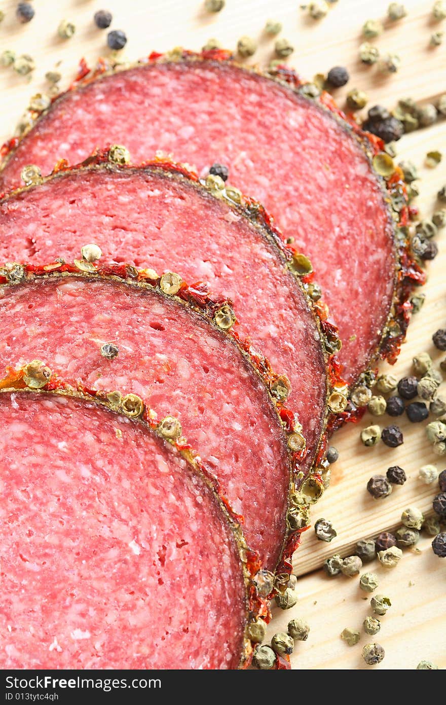 Salami with pepper grains on the white background