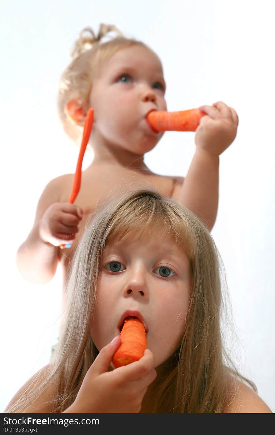 An image of two sisters eating fresh carrot