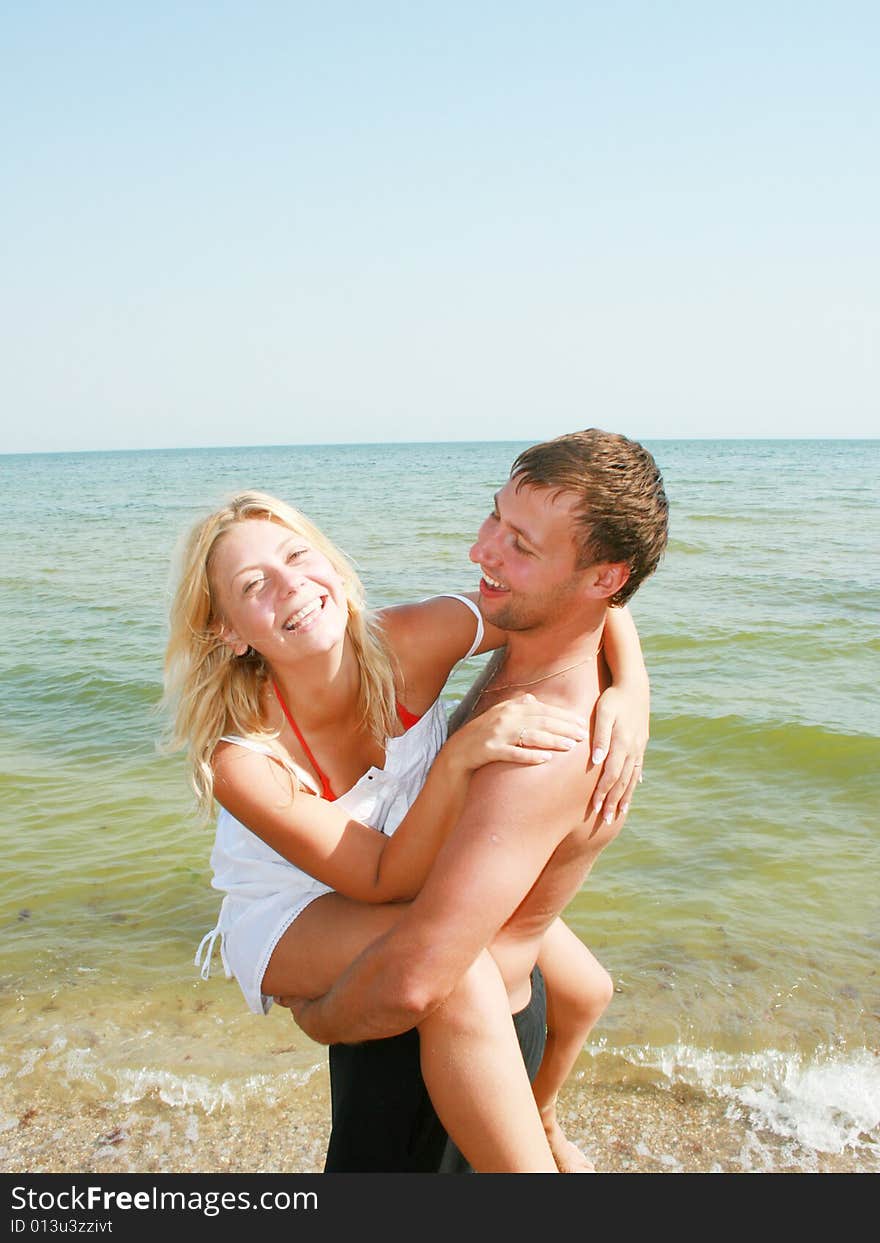 An attractive couple fooling around on the beach, smiling and in love. An attractive couple fooling around on the beach, smiling and in love