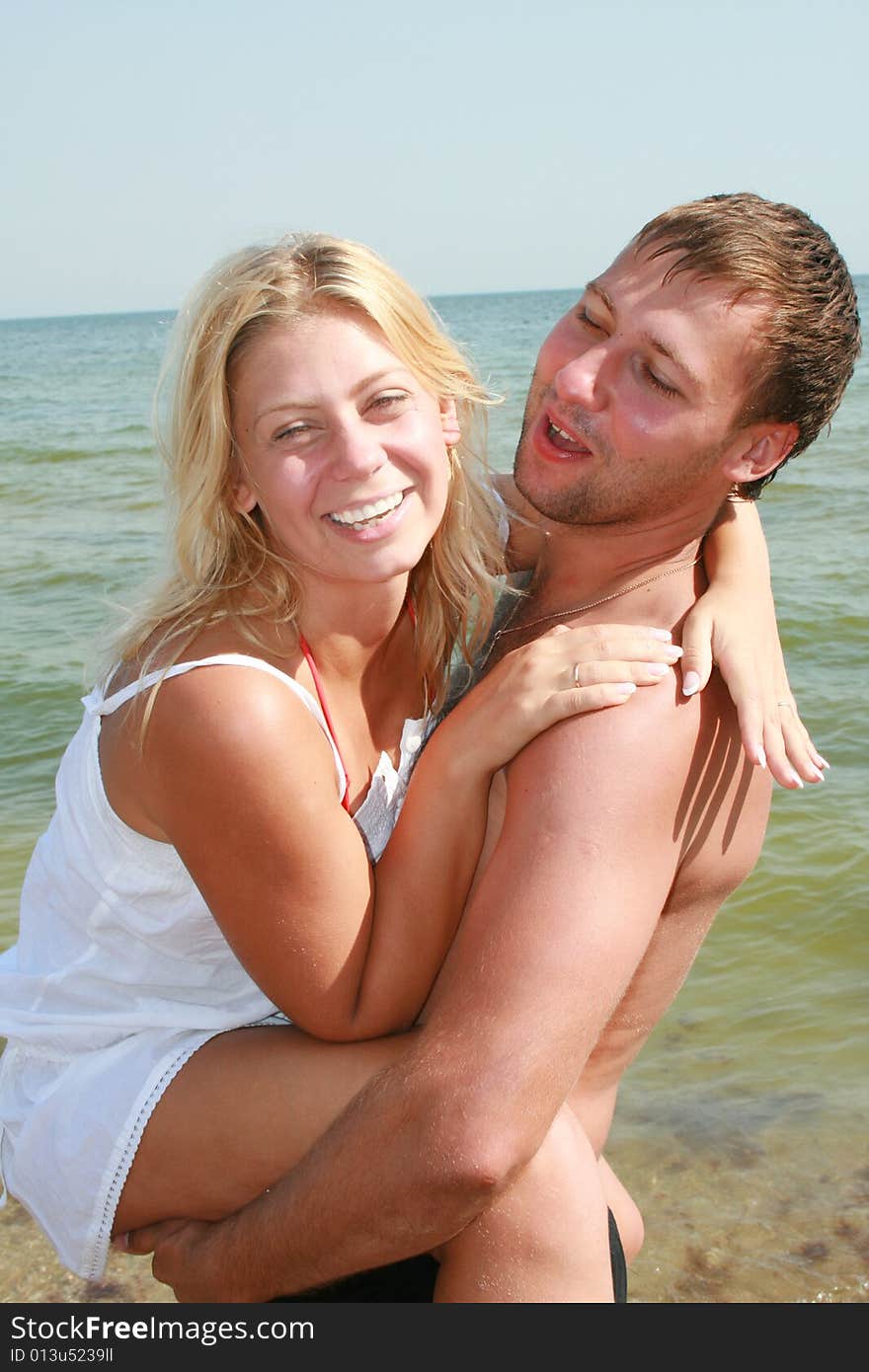 An attractive couple fooling around on the beach, smiling and in love. An attractive couple fooling around on the beach, smiling and in love