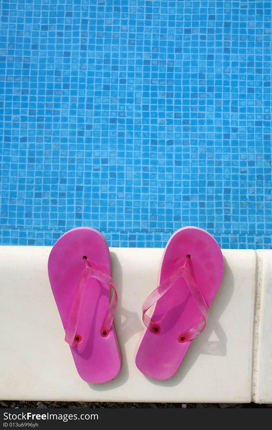 Pink swimming pool sandals on a blue water background