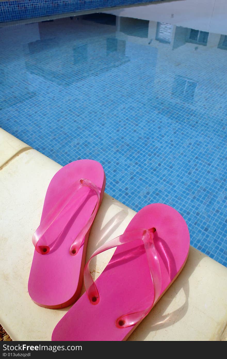 Pink swimming pool sandals on a blue water background