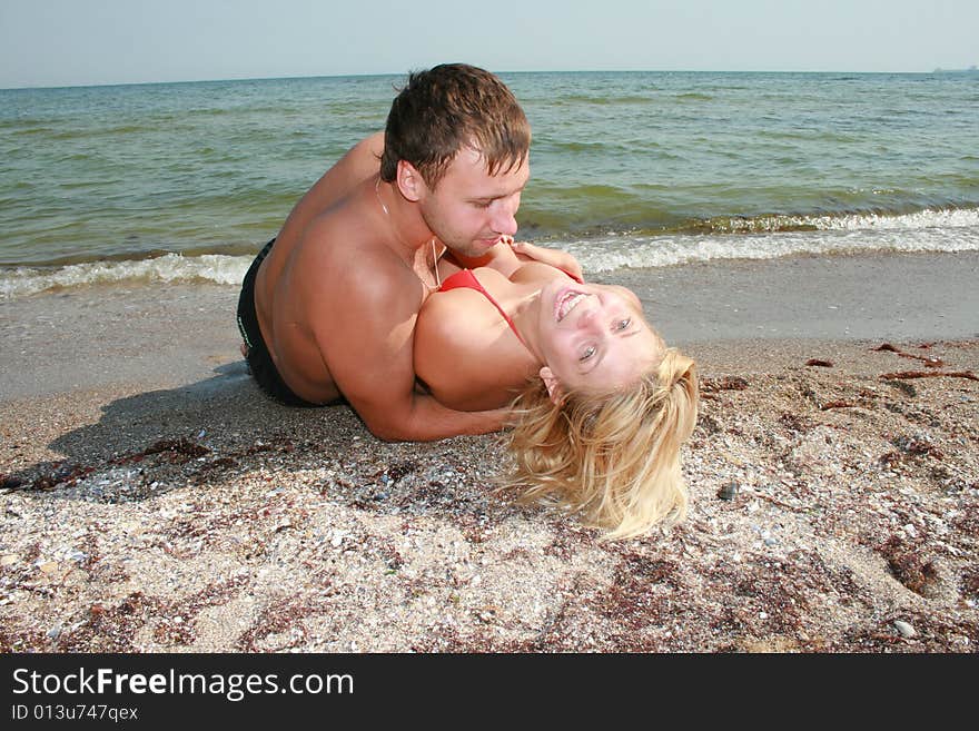 An attractive couple fooling around on the beach, smiling and in love. An attractive couple fooling around on the beach, smiling and in love