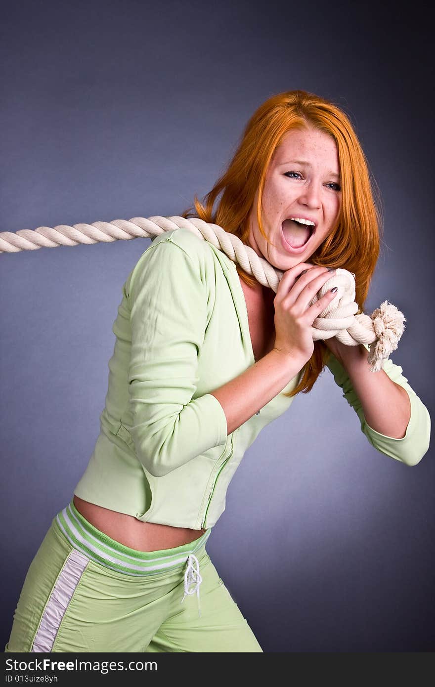 The young woman in a sports suit pulls a rope