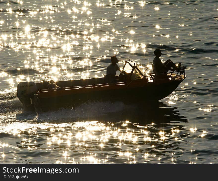 Boat is in the rays of a sun,boat in the reflections of a sun on water