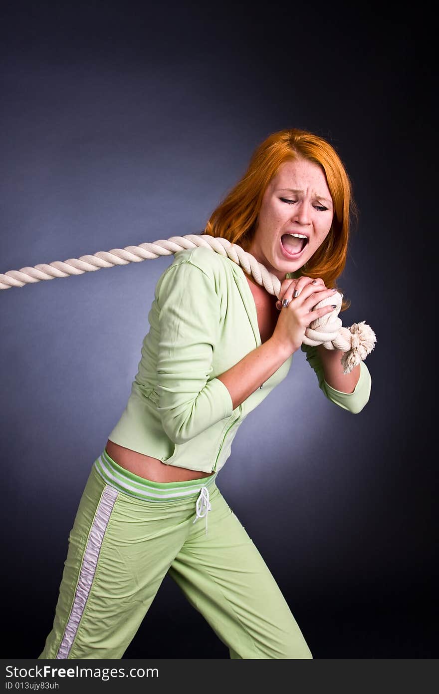 The young woman in a sports suit pulls a rope