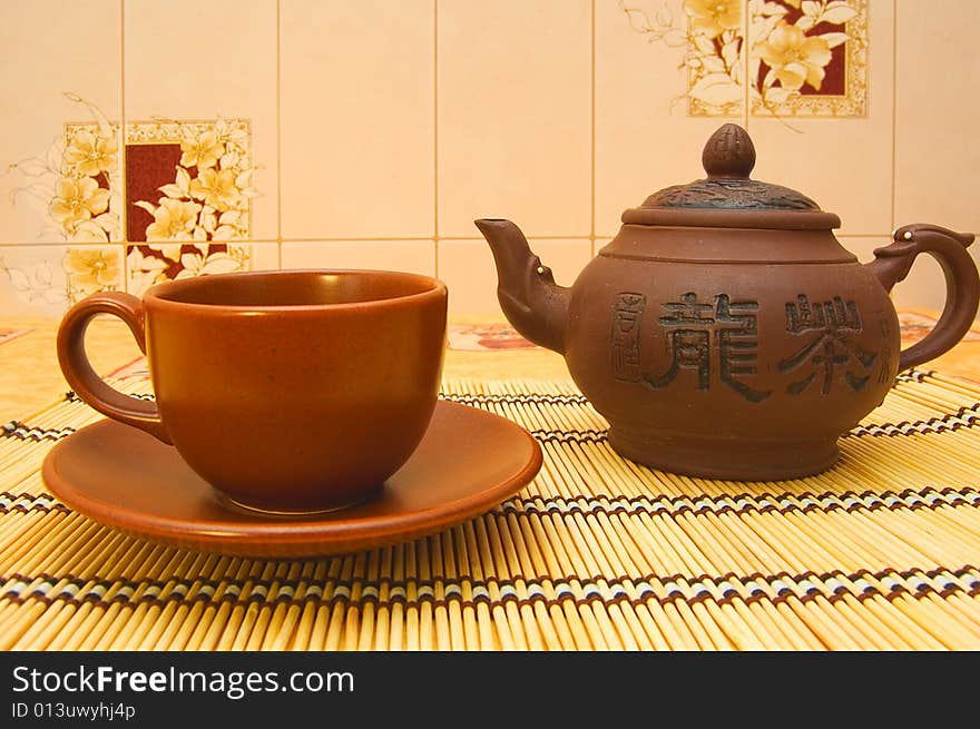 Teapot, cup, saucer on yellow tablecloth. Teapot, cup, saucer on yellow tablecloth