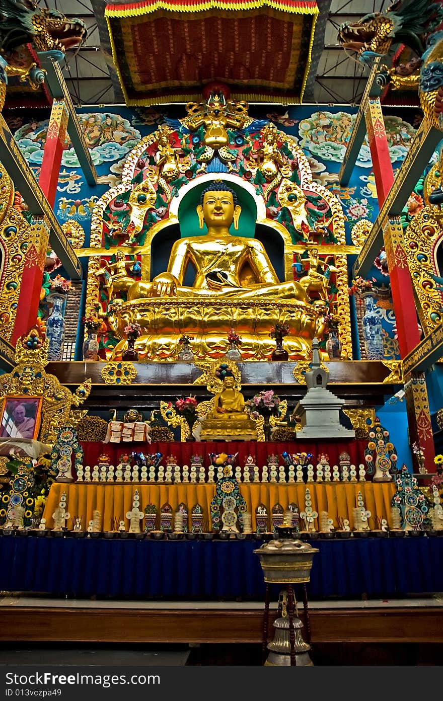 Huge golden colored Budha, in a sitting pose, surrounded by colorful statues in a monastry near Coorg, India. Huge golden colored Budha, in a sitting pose, surrounded by colorful statues in a monastry near Coorg, India