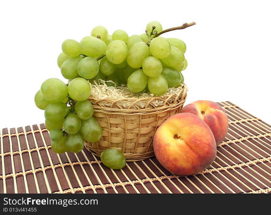 Peaches and grapes in a basket on a napkin