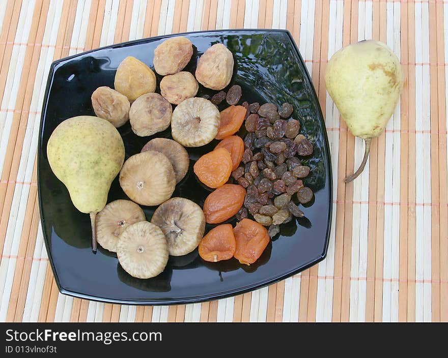 Fruit and pears on a black plate. Fruit and pears on a black plate