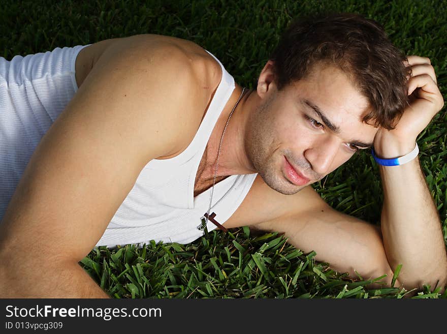 Young man laying on the grass on his side