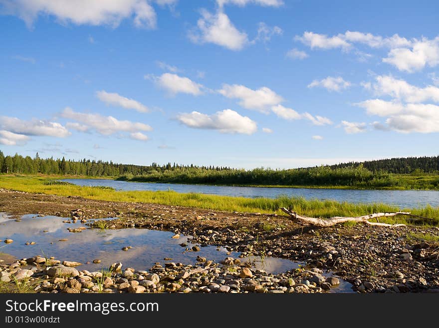 Landscape with log, river and clouds