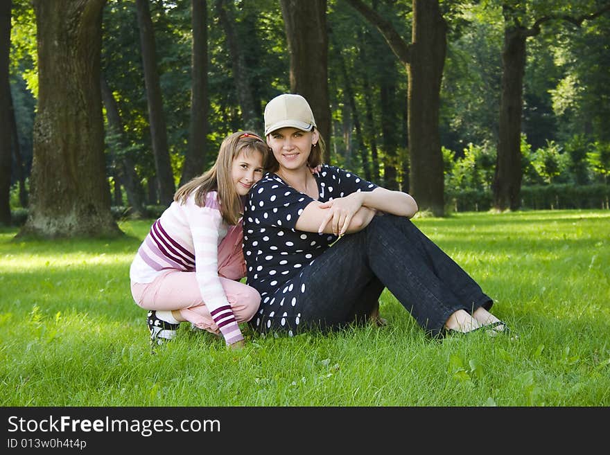 Mother and daughter on lawn in summer's forest.