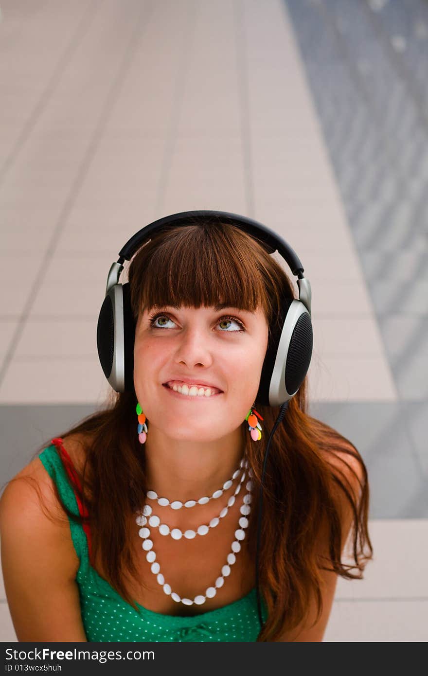 Young pretty girl in big headphones is looking up. Young pretty girl in big headphones is looking up