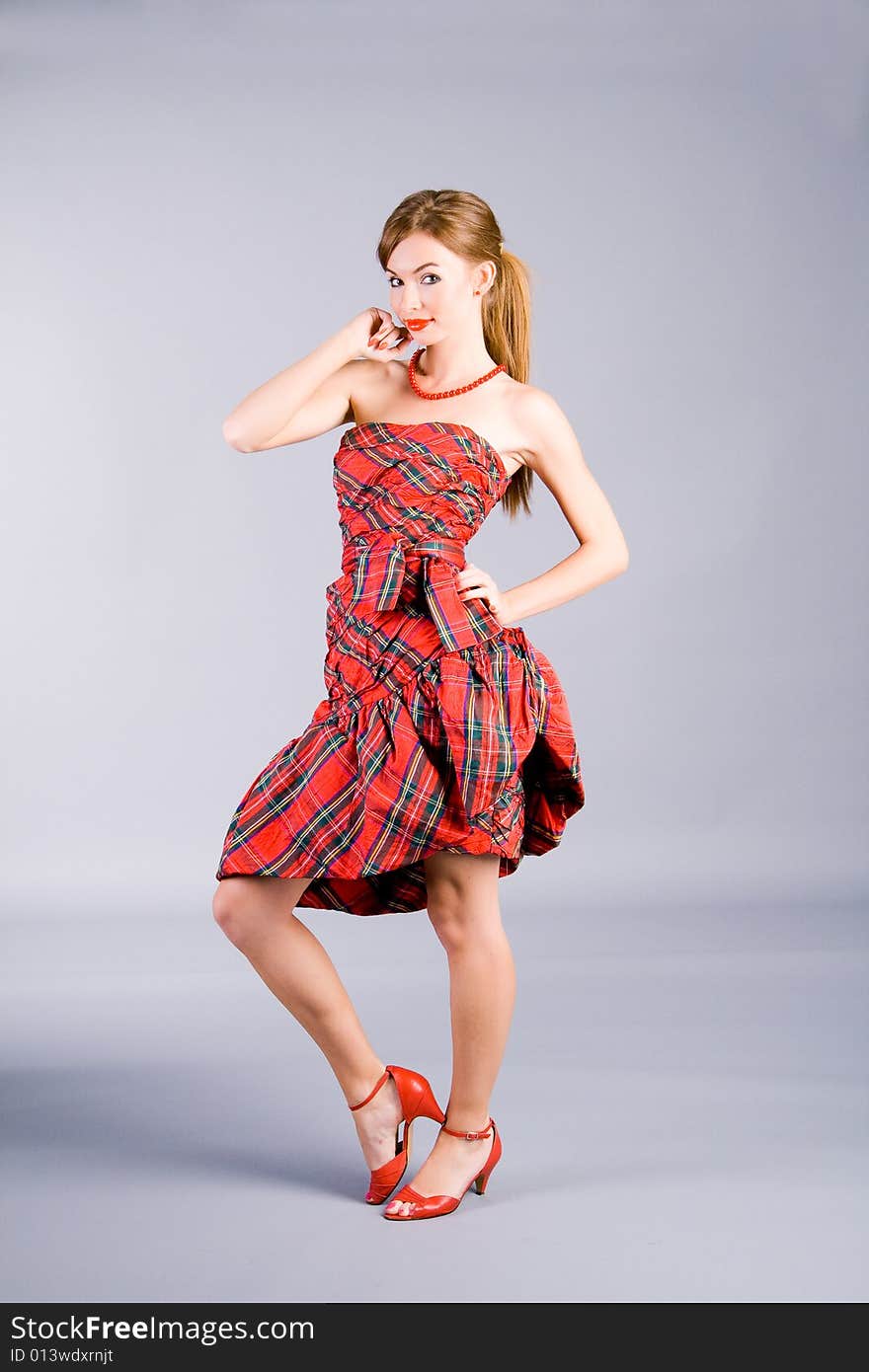 Portrait of the standing girl in red dress on gray background. Portrait of the standing girl in red dress on gray background