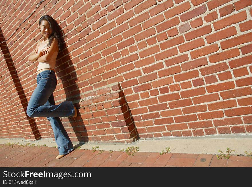 Fashionable young woman against red brick wall. Fashionable young woman against red brick wall.