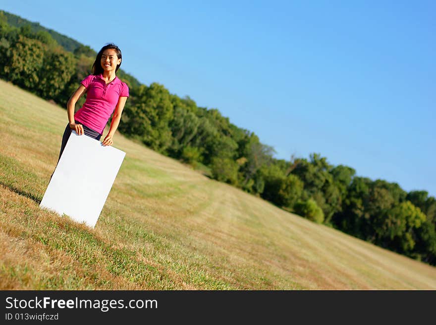 Happy asian girl holding a blank poster. Happy asian girl holding a blank poster.