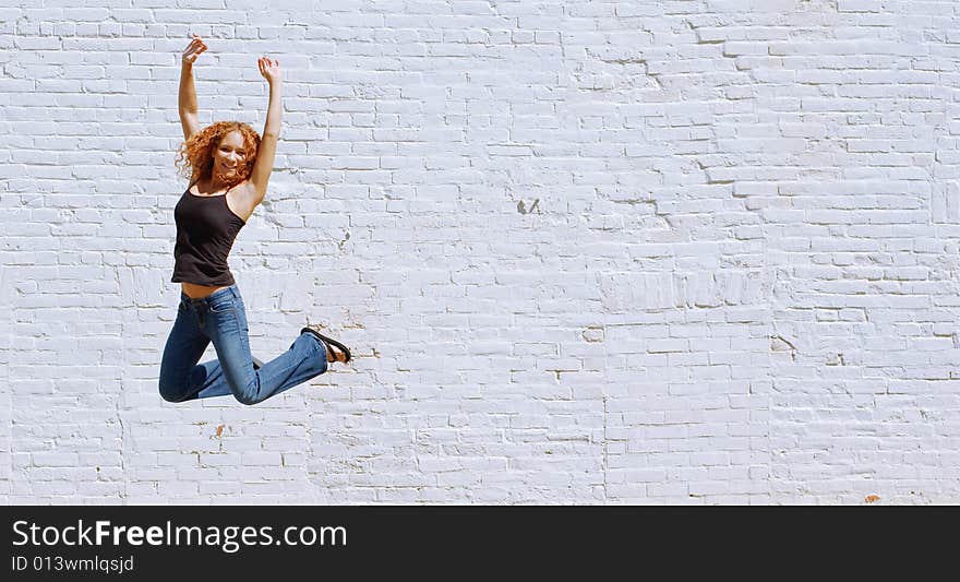 Attractive urban girl against white brick wall.