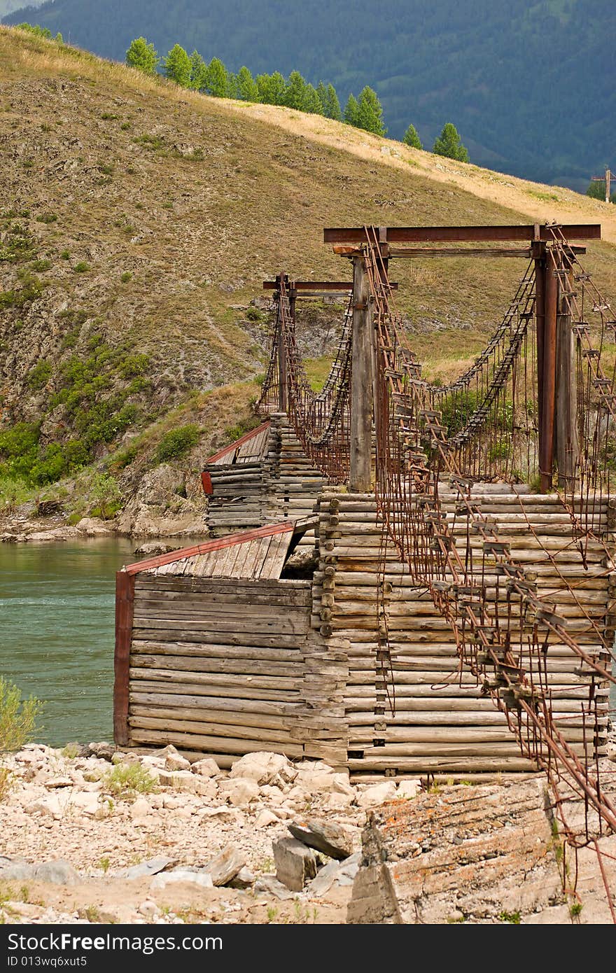 Old suspension bridge above river in mountains