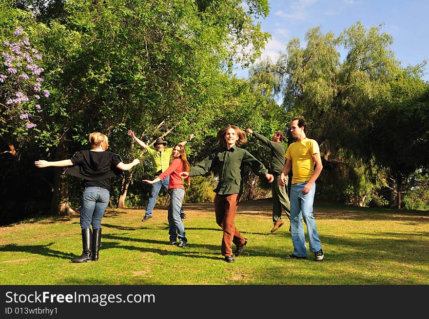 Group of six friends spinning around and jumping in a park. Group of six friends spinning around and jumping in a park