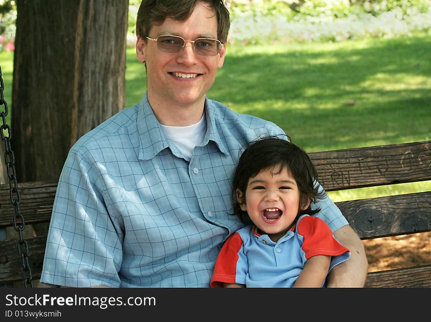 Father and son enjoying swinging in the park together