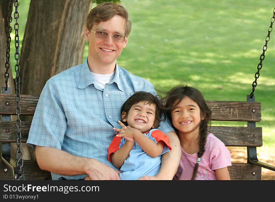 Father and his children enjoying swinging in the park