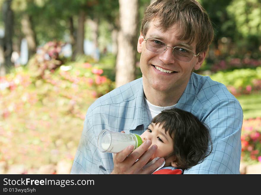 Father feeding his baby a bottle in the park