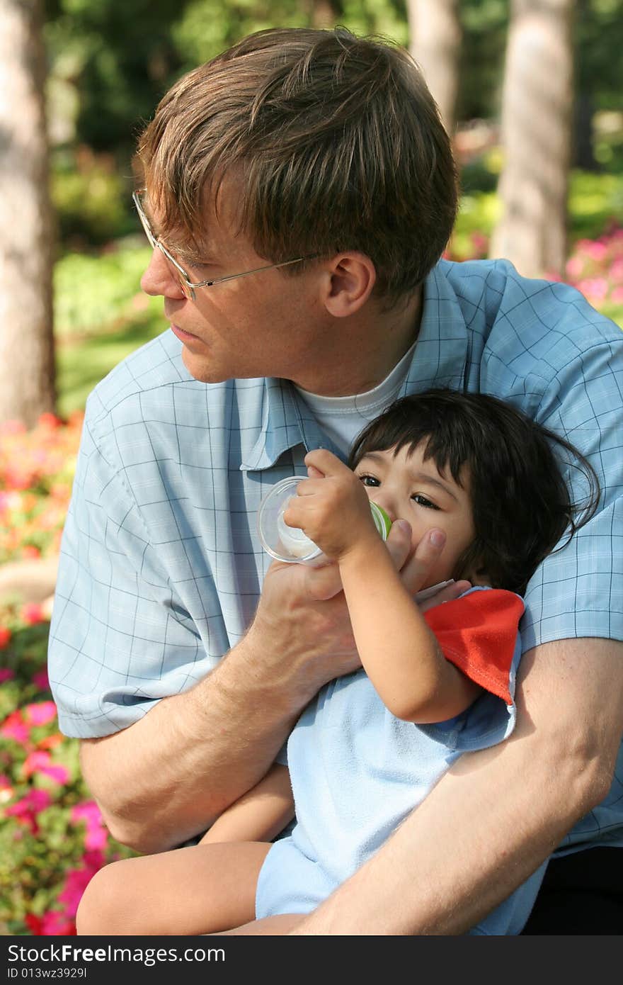 Father feeding baby a bottle in the park