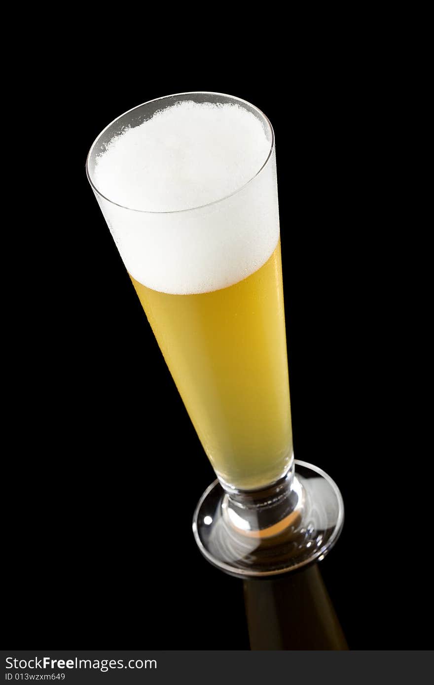 High angle view of a light beer in a tall glass isolated on a black background. High angle view of a light beer in a tall glass isolated on a black background