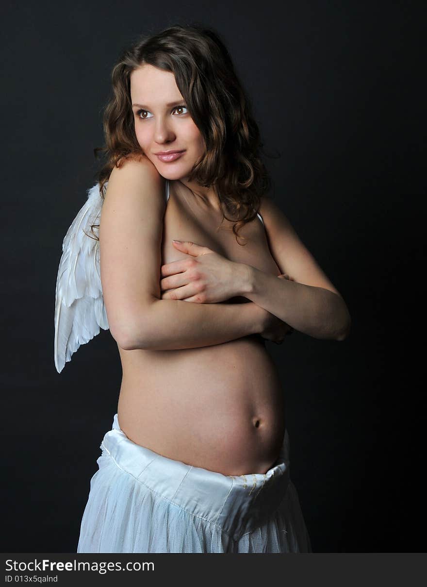 Pregnant woman on a black background with angel wings