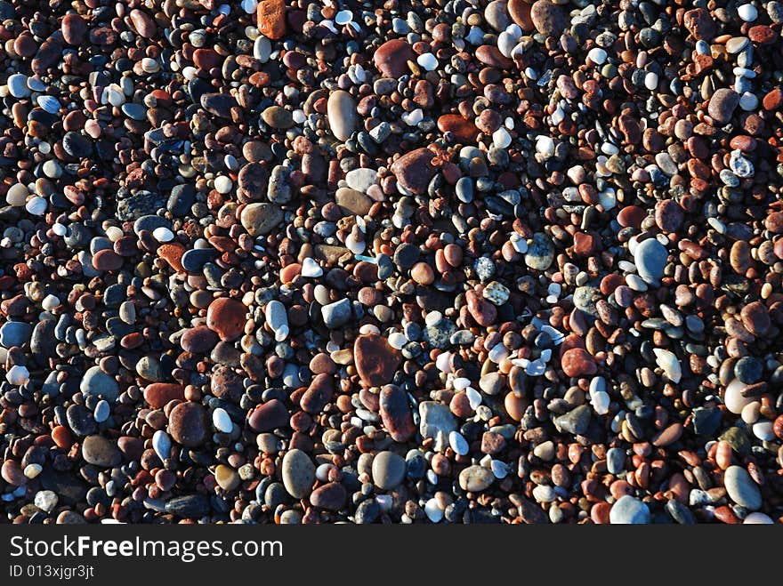 Colourful pebbles on a shore in morning sun. Colourful pebbles on a shore in morning sun