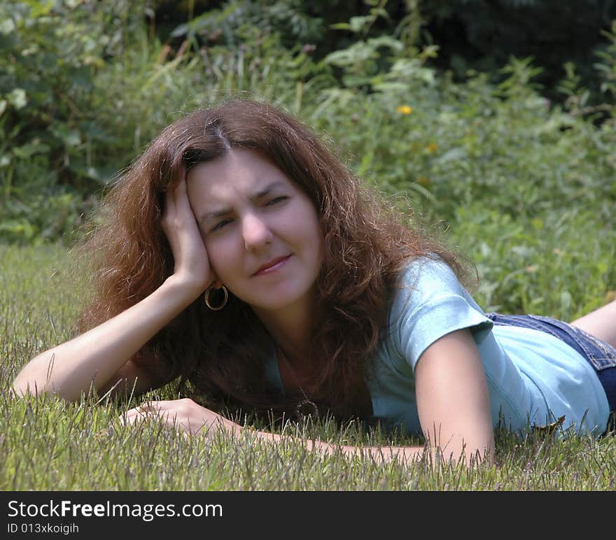 Young woman lying on the grass thinking