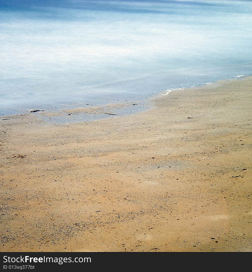 Long exposure photograph showing the movement of waves crashing on a beach.