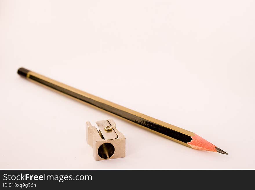 Black and gold lead pencil with a metal pencil sharpener on a white background. Black and gold lead pencil with a metal pencil sharpener on a white background